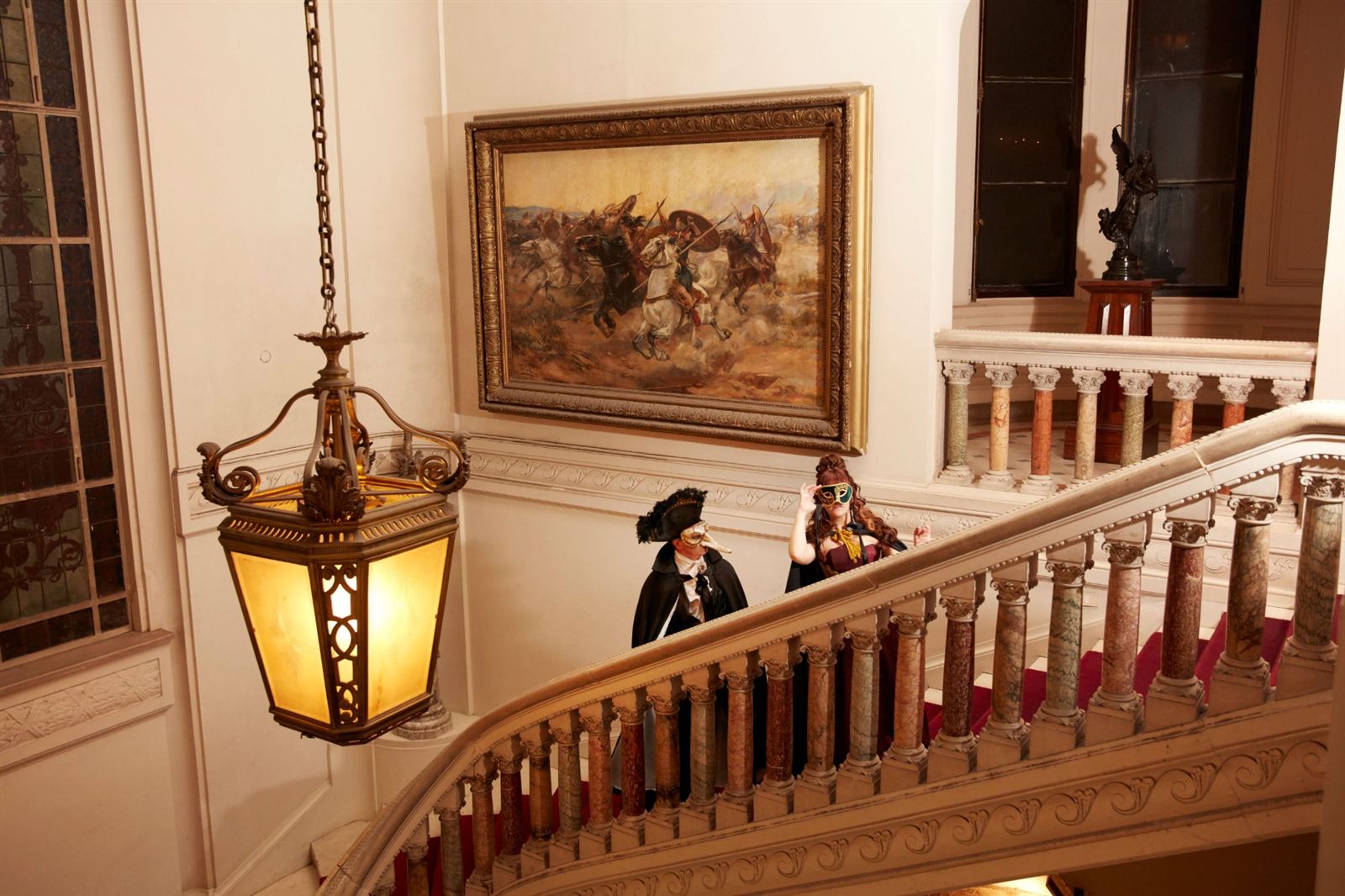 Figuras con máscaras venecianas en la escalera monumental del palacio